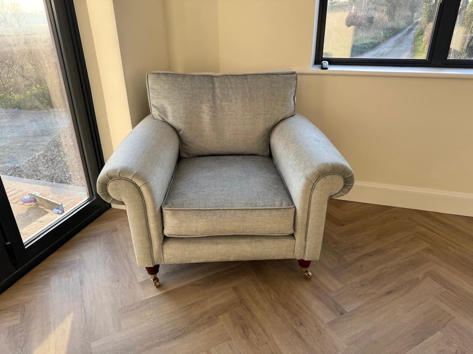 Reupholstered armchair in soft grey fabric with turned mahogany legs and brass castors